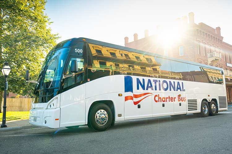 A charter bus with National Charter Bus branding parks on a city street