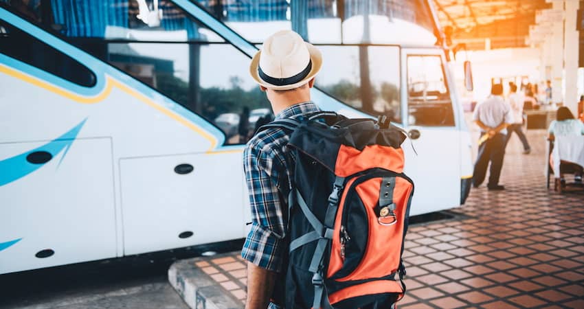 a camper with a backpack prepares to board a private charter bus