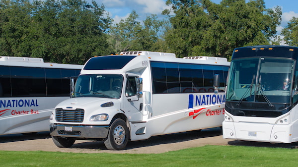 three shuttle buses parked, with National logos on them