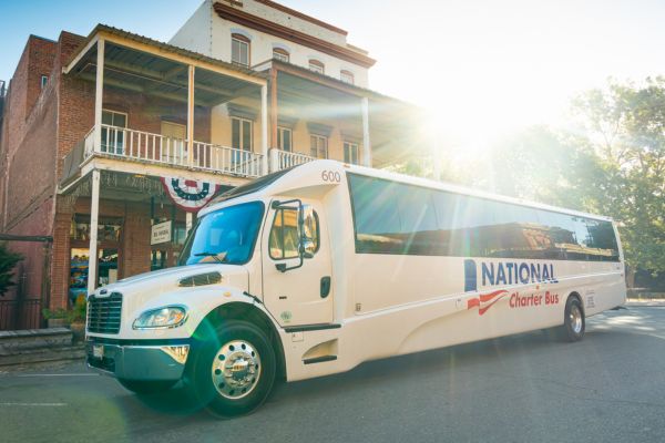 Chic shuttle bus rental parked outside a historic building at sunset