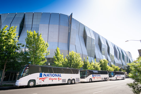 three large charter buses pull up to a stadium