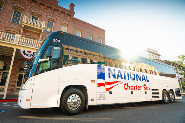 a large charter bus with the sun setting behind it