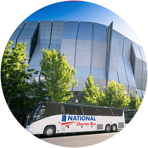 a "national charter bus" bus parked outside of a large arena