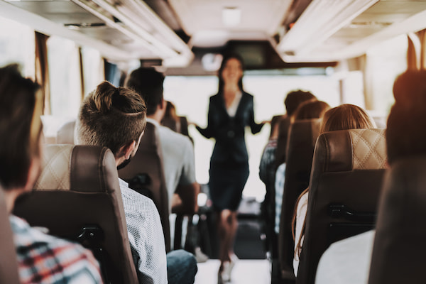 employees watch and listen to a guide on a shuttle bus