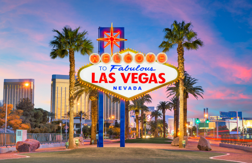 Famous Las Vegas sign with the cityscape blurred in the background at night