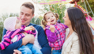 A family with two children smile in an amusement park