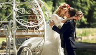 Bride and groom kiss as they exit a white carriage